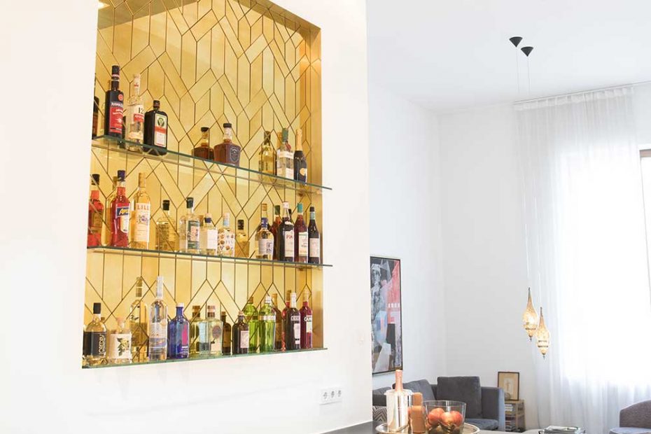 Eine edle moderne Bar mit 3 Abstellflächen für Flaschen, bestehend aus vielen mit Facetten geschliffenen aufgeklebten goldenen Antikspiegel Teilen in einem Rahmen aus Messing, eingelassen in die Wand.