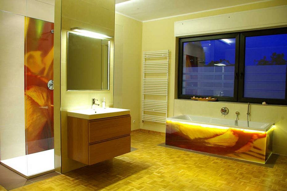 View of the bathroom in the evening. Here, the special LED lighting on the edge of the bathtub on the glass surfaces comes into its own.