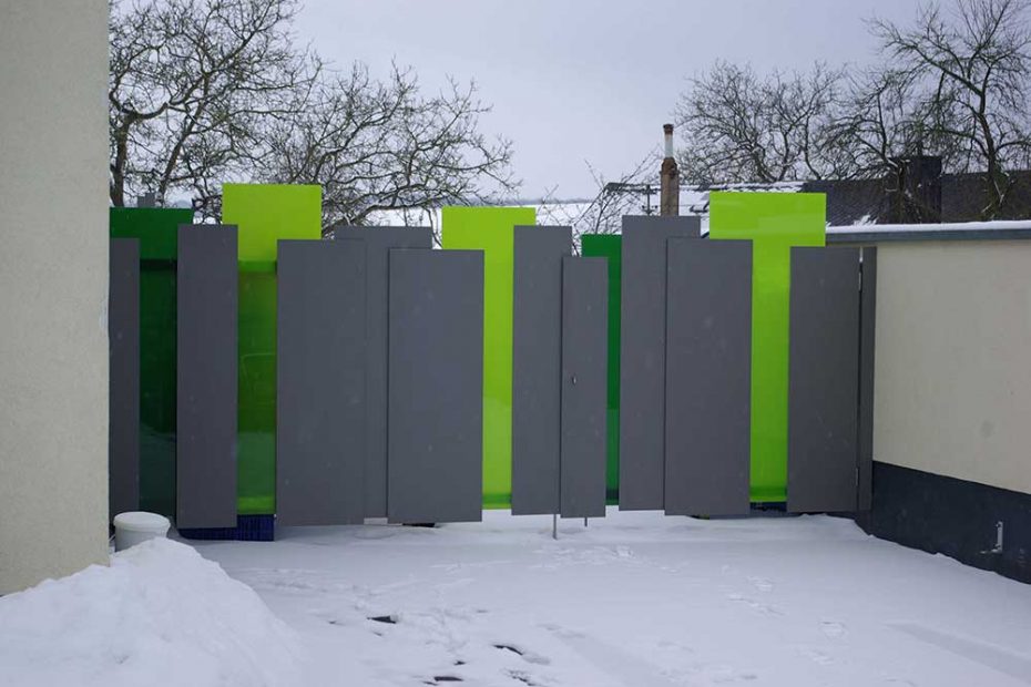 A large gate made of powder-coated stainless steel and safety glass with green color foils lamenated in between the glass sheets.