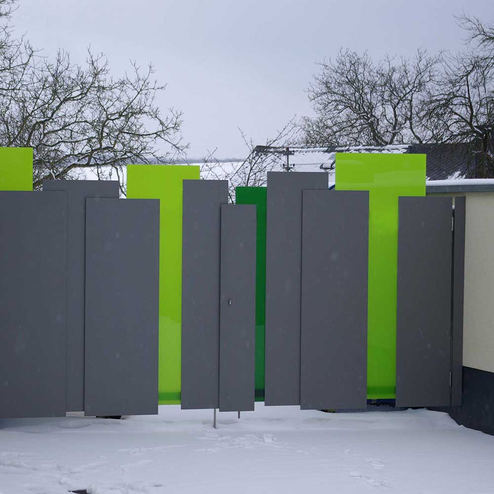A large gate made of powder-coated stainless steel and safety glass with green color foils lamenated in between the glass sheets.