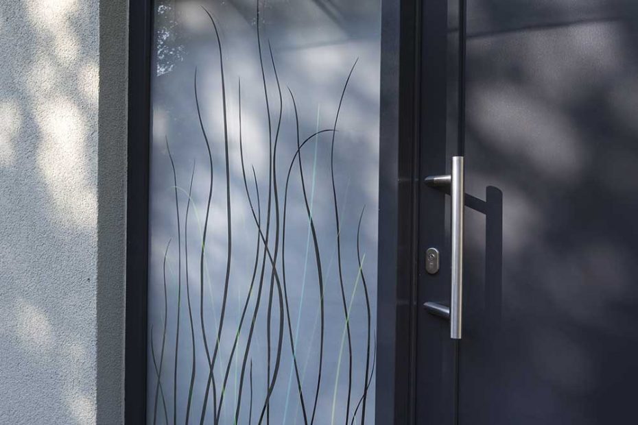 The side panel of the front door is designed with melted green glass grass, laminated in a partly matt double glazing. The panel is clear in the upper area and matt at the bottom.
