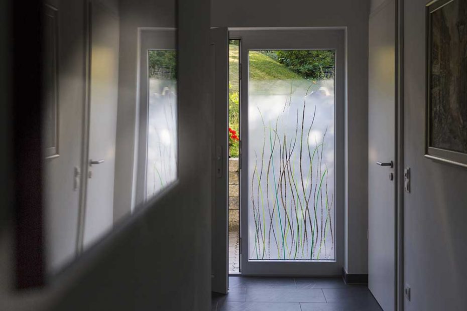 View from a hallway. The side panel of the entrance door is designed with green colored glass grass and matt glass.