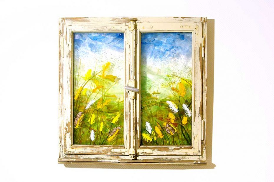 An artistically designed, closed, old wooden window with plants and grasses melted from colored glass.